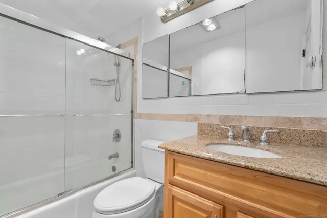 a bathroom with a granite countertop sink toilet and shower