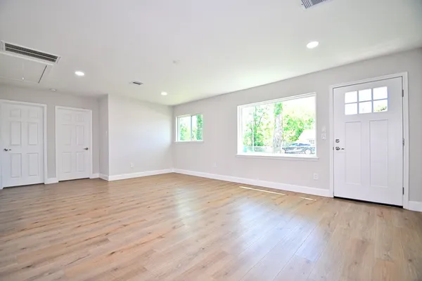 an empty room with wooden floor and windows