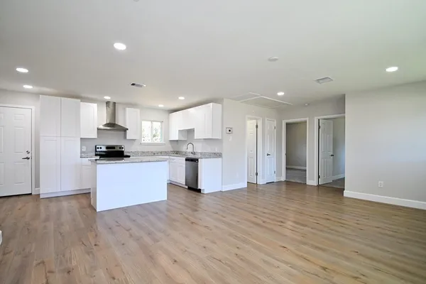 a large kitchen with stainless steel appliances granite countertop a large counter top a sink and a refrigerator