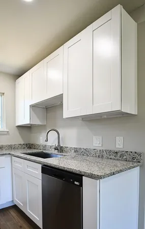 a kitchen with granite countertop white cabinets and a sink