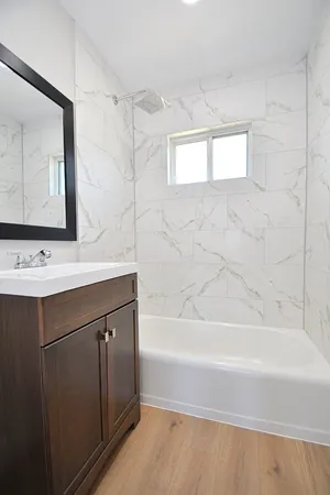 a bathroom with a bathtub sink vanity and mirror