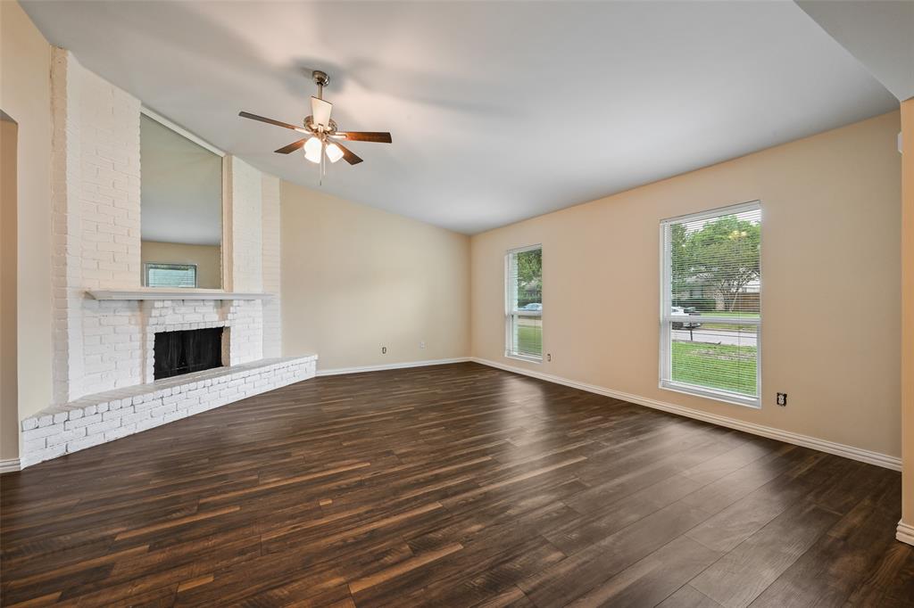 7318 Emory Oak Lane Dallas, TX 75249 - Photo 22 of 28 Living space featuring wood-finish flooring, a white brick fireplace with hearth, and a vaulted ceiling with a ceiling fan