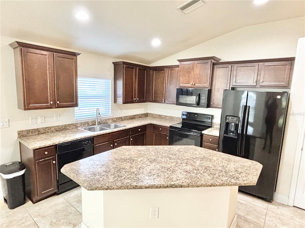 13231 Precept Way Hudson, FL 34669 - Photo 4 of 30 a kitchen with stainless steel appliances granite countertop a sink a stove a refrigerator a washer and dryer
