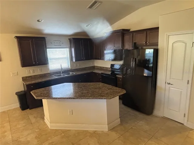 a kitchen with stainless steel appliances granite countertop a sink and a refrigerator