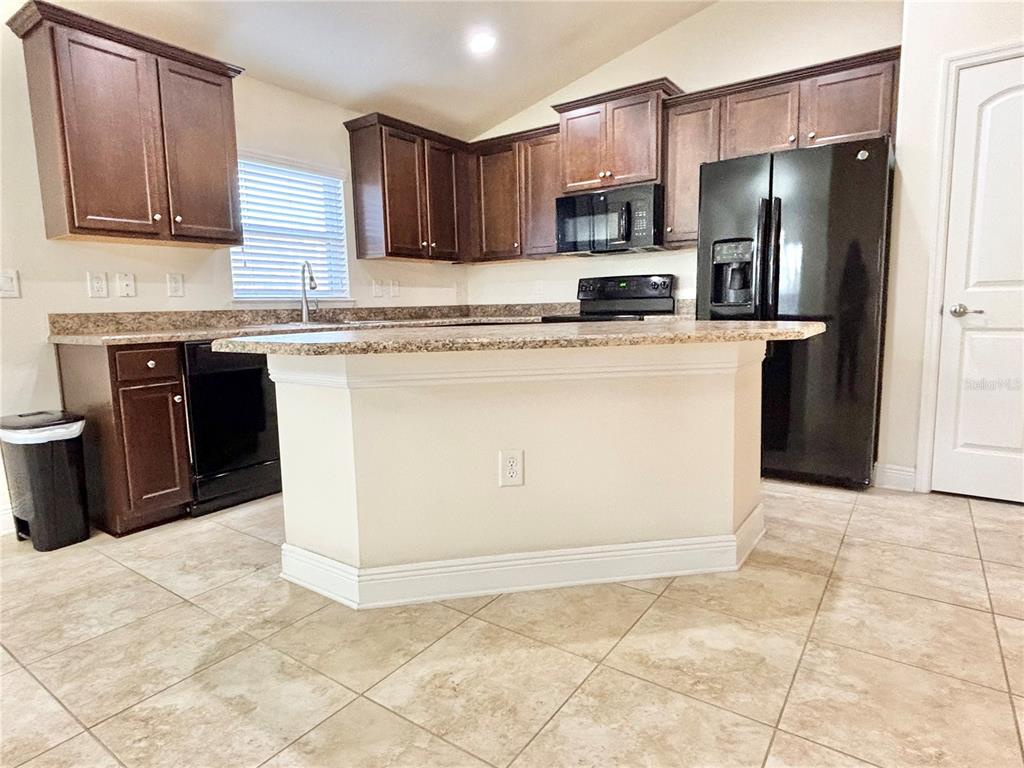 13231 Precept Way Hudson, FL 34669 - Photo 6 of 30 a kitchen with stainless steel appliances granite countertop a stove a refrigerator a sink a microwave and island
