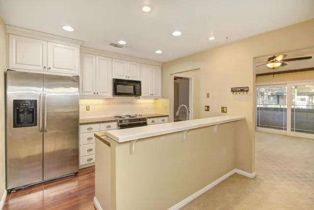 a kitchen with stainless steel appliances granite countertop a refrigerator a stove and a sink