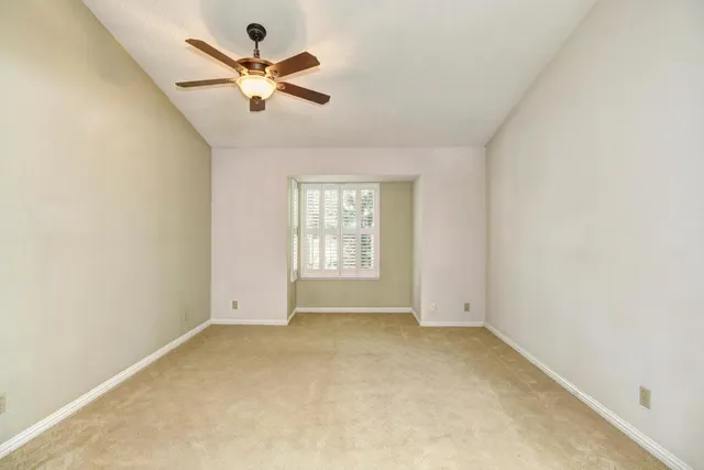 an empty room with a ceiling fan and window