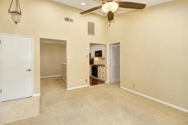 a view of a livingroom with a chandelier fan and kitchen view