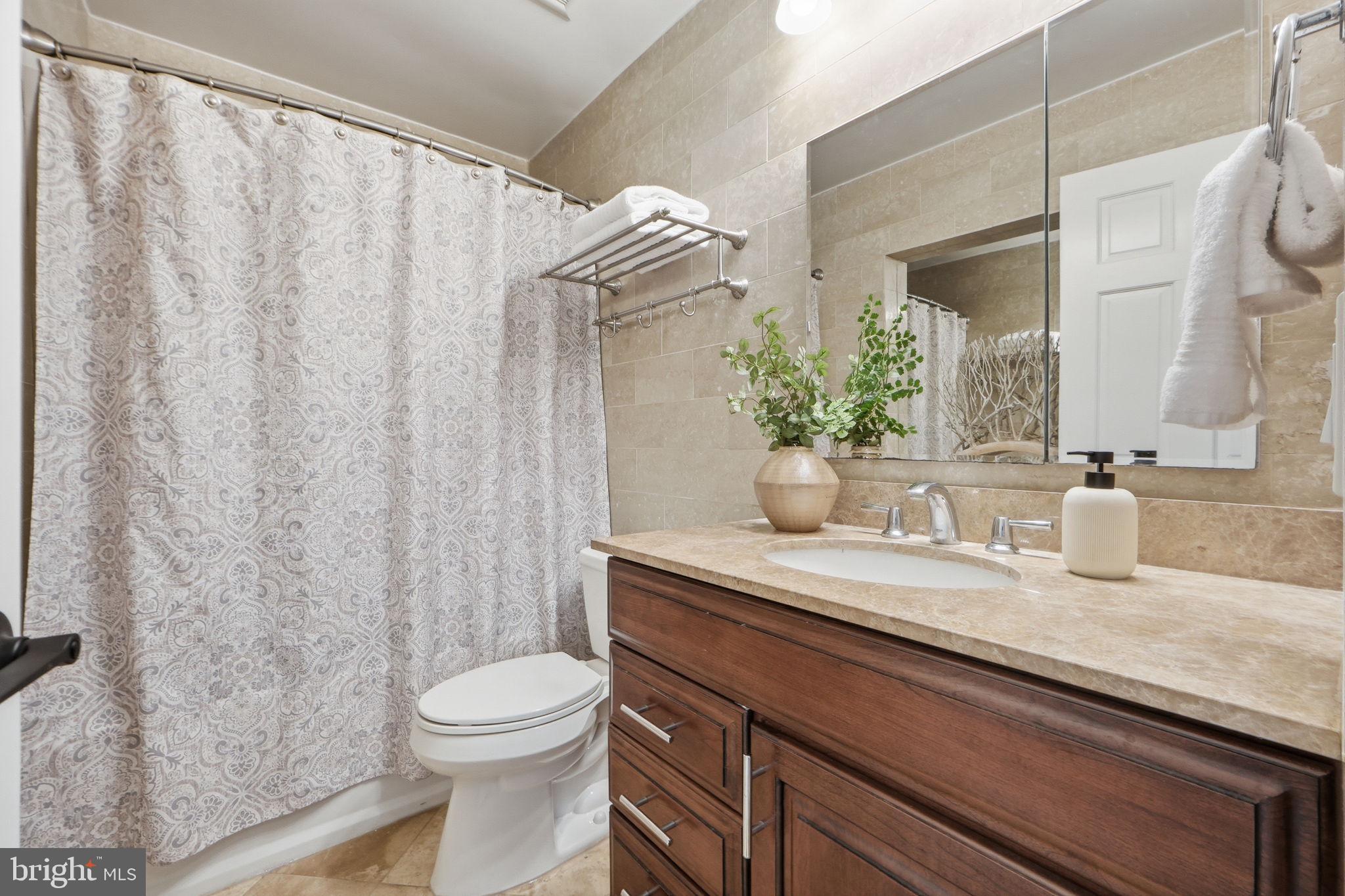 8230 Carrleigh Parkway, Unit 84 Springfield, VA 22152 - Photo 17 of 28 a bathroom with a granite countertop sink a toilet and a mirror