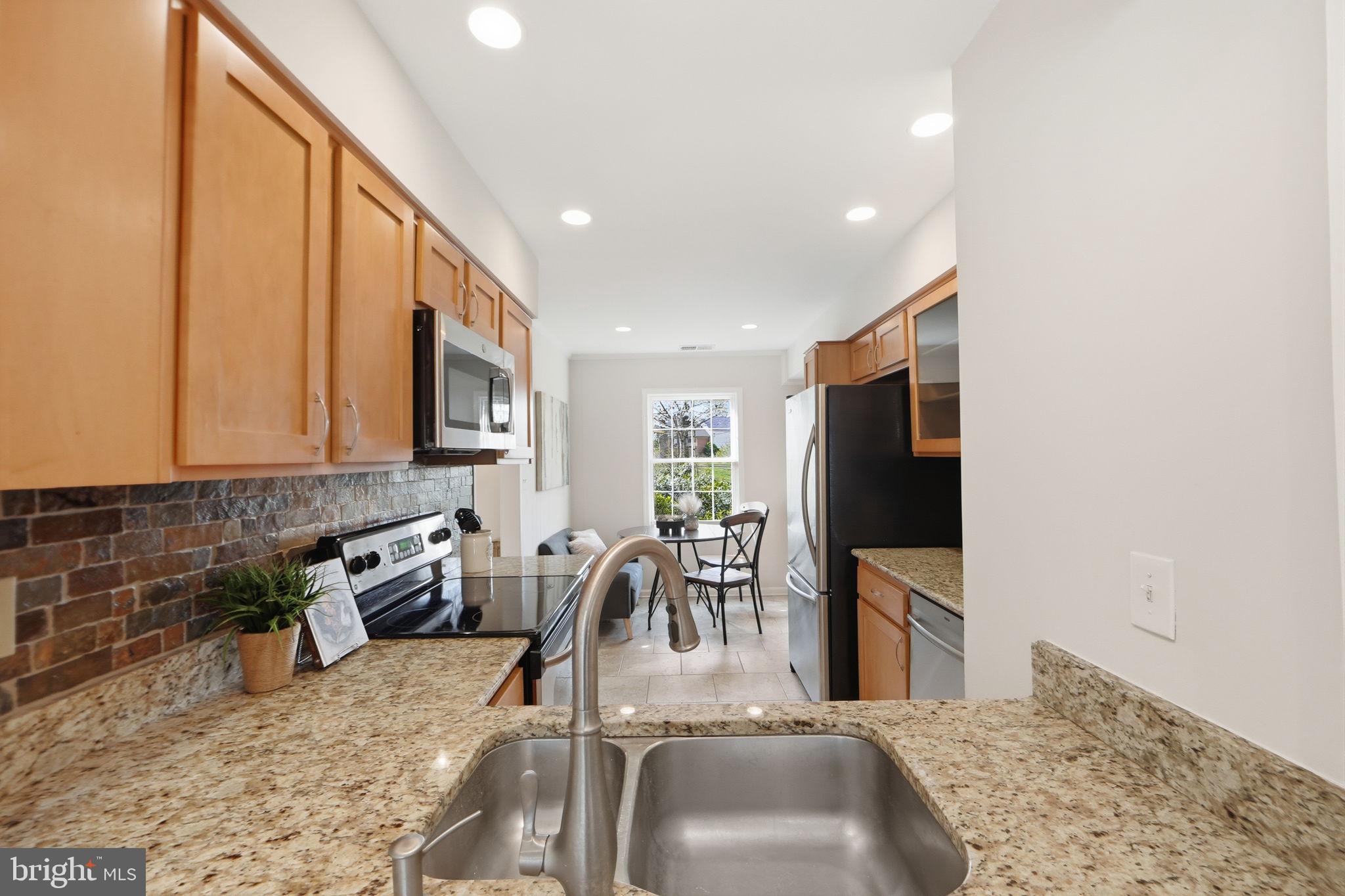 8230 Carrleigh Parkway, Unit 84 Springfield, VA 22152 - Photo 8 of 28 a kitchen with stainless steel appliances granite countertop a sink stove and microwave