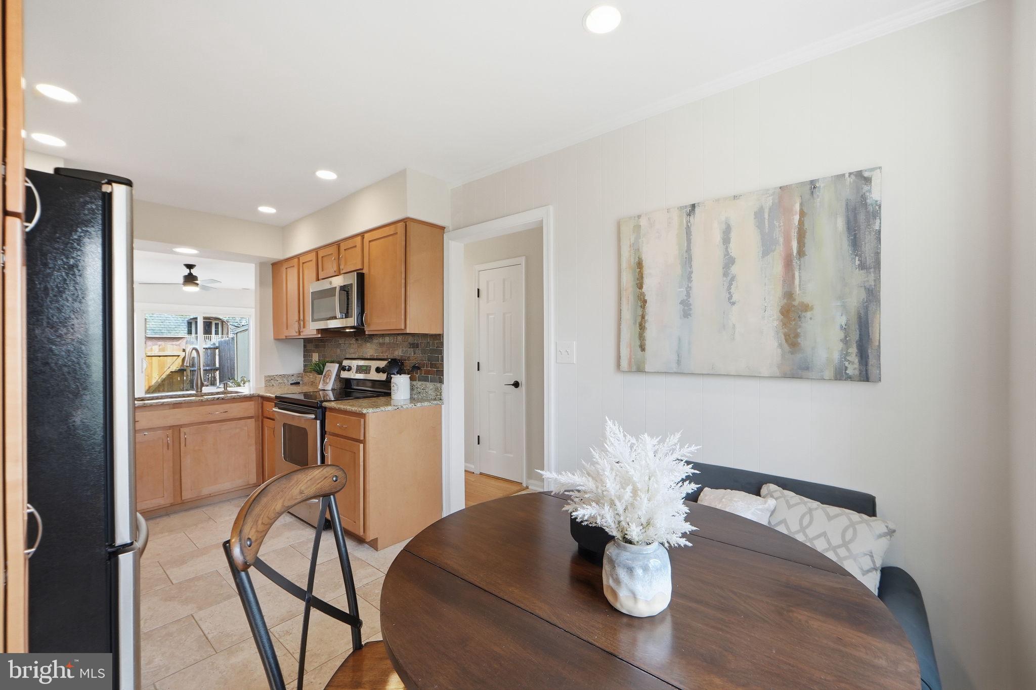 8230 Carrleigh Parkway, Unit 84 Springfield, VA 22152 - Photo 10 of 28 a kitchen with stainless steel appliances granite countertop a refrigerator a stove a microwave oven a dining table and chairs with wooden floor