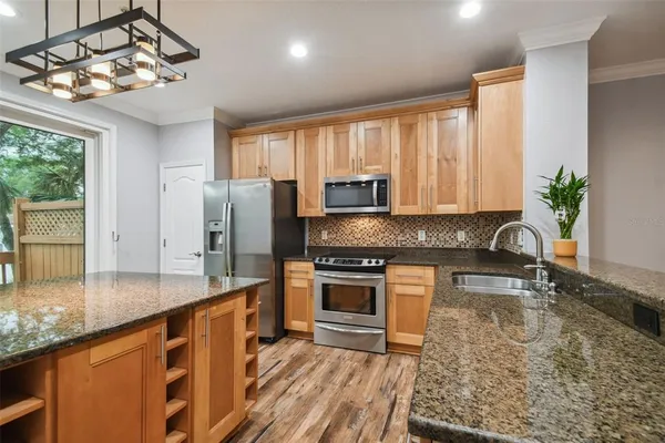 a kitchen with stainless steel appliances granite countertop a sink a stove top oven a counter space and cabinets