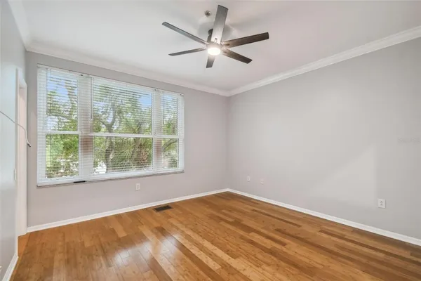 a view of empty room with wooden floor and fan