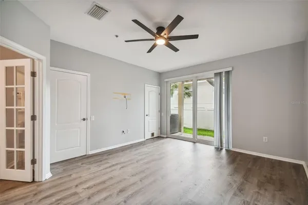a view of an empty room with wooden floor and a ceiling fan