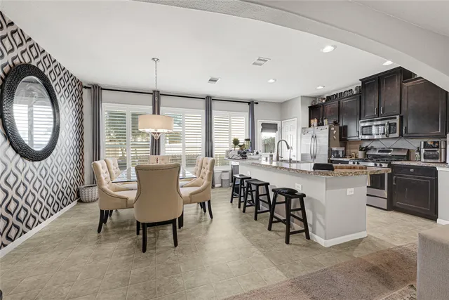 a kitchen with kitchen island granite countertop a stove a sink a oven a dining table and chairs