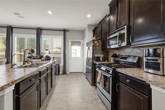 a kitchen with stainless steel appliances granite countertop a sink a stove and a refrigerator