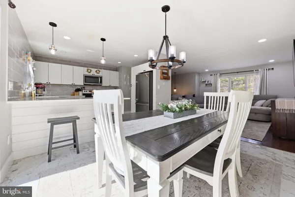a view of a dining room and livingroom with furniture wooden floor a chandelier