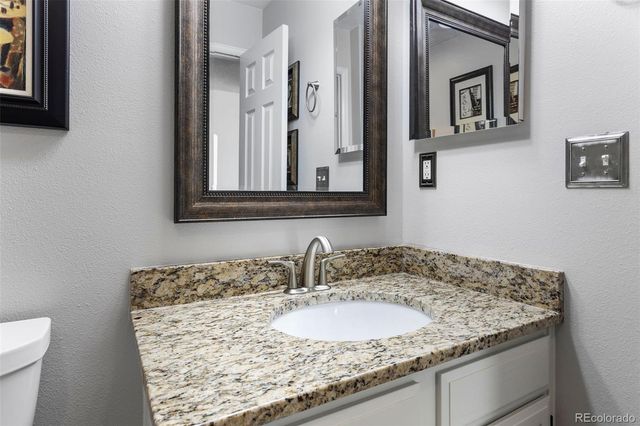a bathroom with a granite countertop sink and a toilet