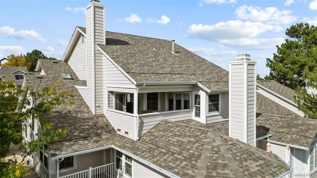 a view of a white house with a small yard and wooden fence