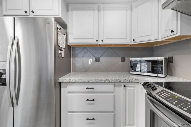 a kitchen with granite countertop a refrigerator and cabinets