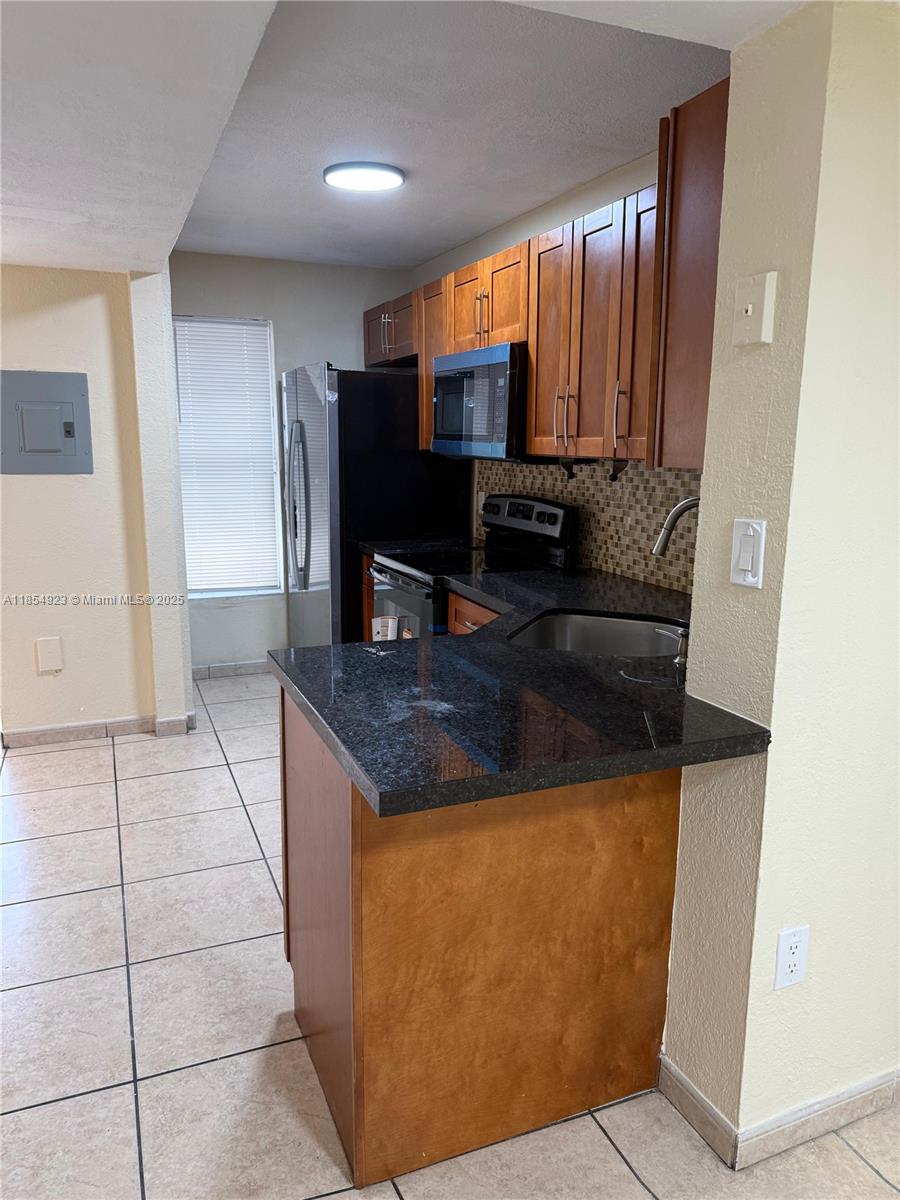 2310 West 60th Street, Unit 9G Hialeah, FL 33016 - Photo 6 of 15 a kitchen with kitchen island granite countertop a sink a stove and a refrigerator