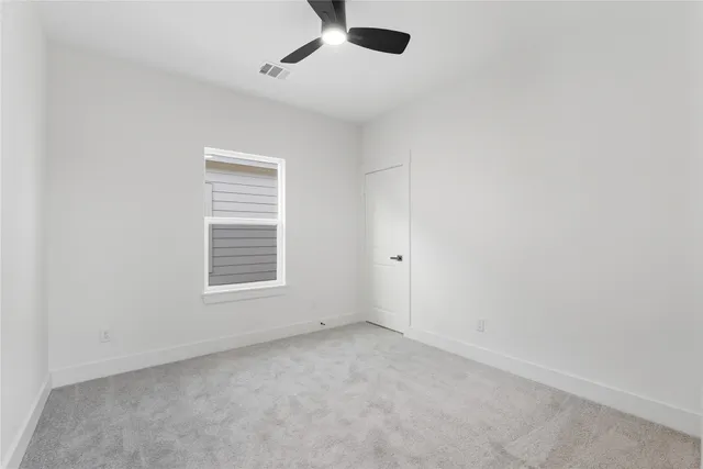an empty room with a window and a ceiling fan