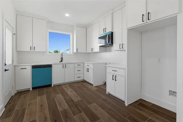 a kitchen with white cabinets and window