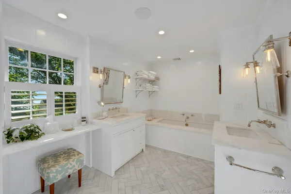 a spacious bathroom with a double vanity sink a large mirror and a bathtub