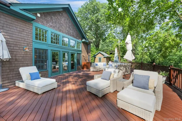 a view of a patio with couches table and chairs with wooden floor and fence