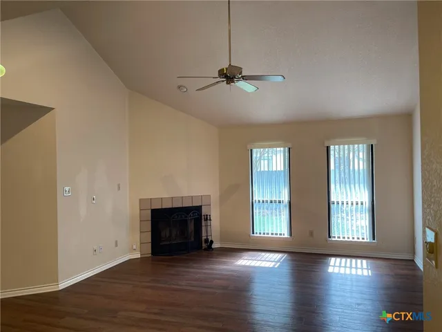an empty room with wooden floor fireplace and windows