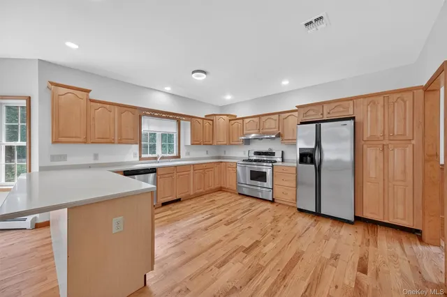 a kitchen with stainless steel appliances granite countertop a refrigerator a sink dishwasher a stove with large oven and wooden floors