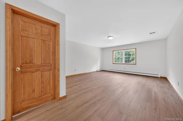an empty room with wooden floor closet and windows