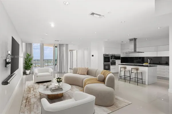 a living room with furniture white walls and kitchen view