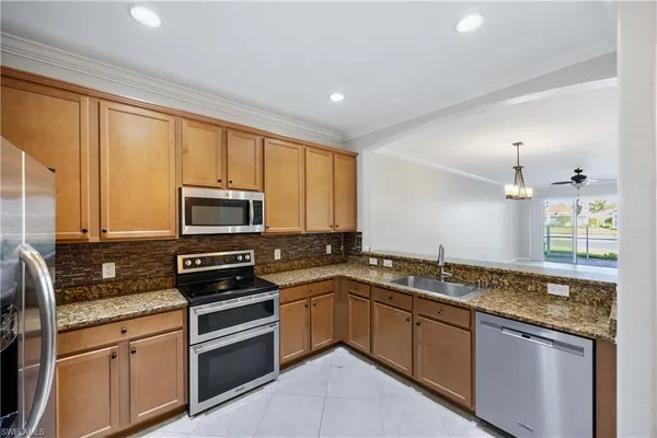a kitchen with stainless steel appliances granite countertop a sink stove microwave and refrigerator