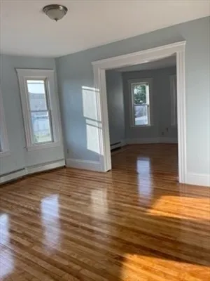 a view of empty room with window and wooden floor