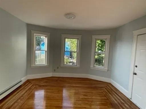 a view of an empty room with wooden floor and a window