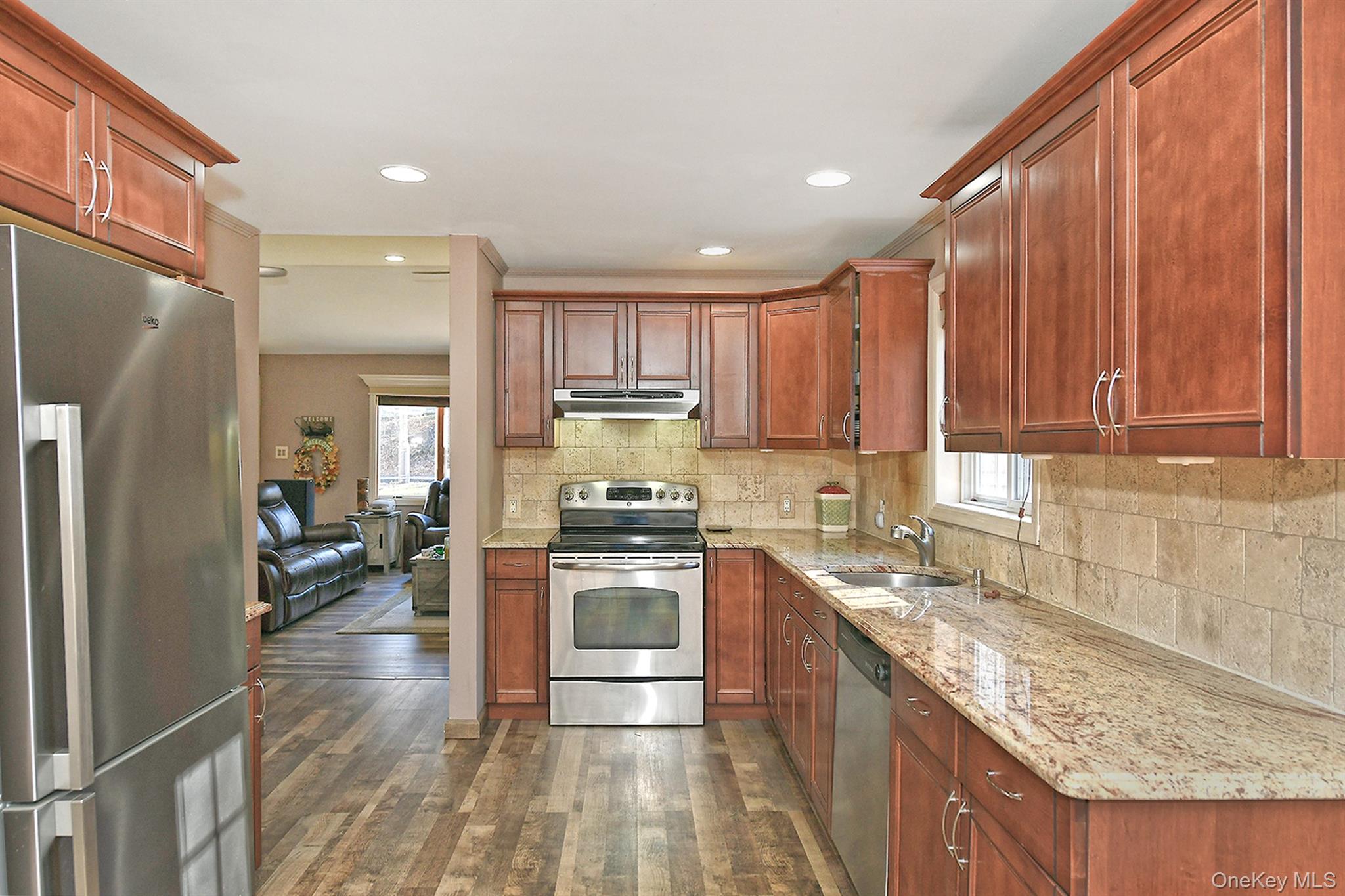150 Hallock Landing Road Rocky Point, NY 11778 - Photo 13 of 36 Kitchen with appliances with stainless steel finishes, light stone counters, dark wood-type flooring, brown cabinets, and under cabinet range hood