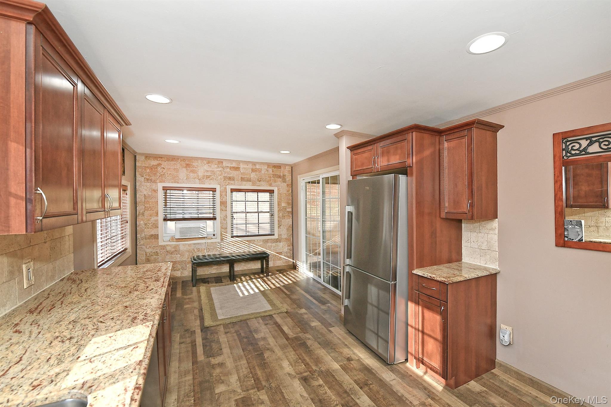 150 Hallock Landing Road Rocky Point, NY 11778 - Photo 15 of 36 Kitchen with freestanding refrigerator, backsplash, brown cabinets, light stone countertops, and dark wood-style floors
