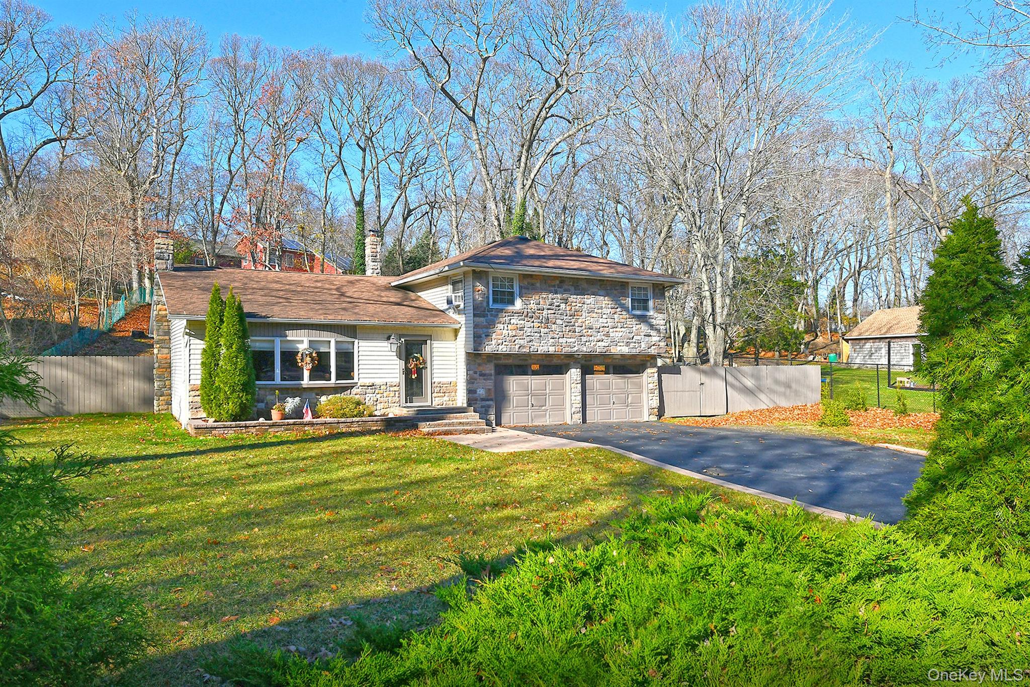 150 Hallock Landing Road Rocky Point, NY 11778 - Photo 3 of 36 Split level home with stone siding, asphalt driveway, a chimney, and an attached garage