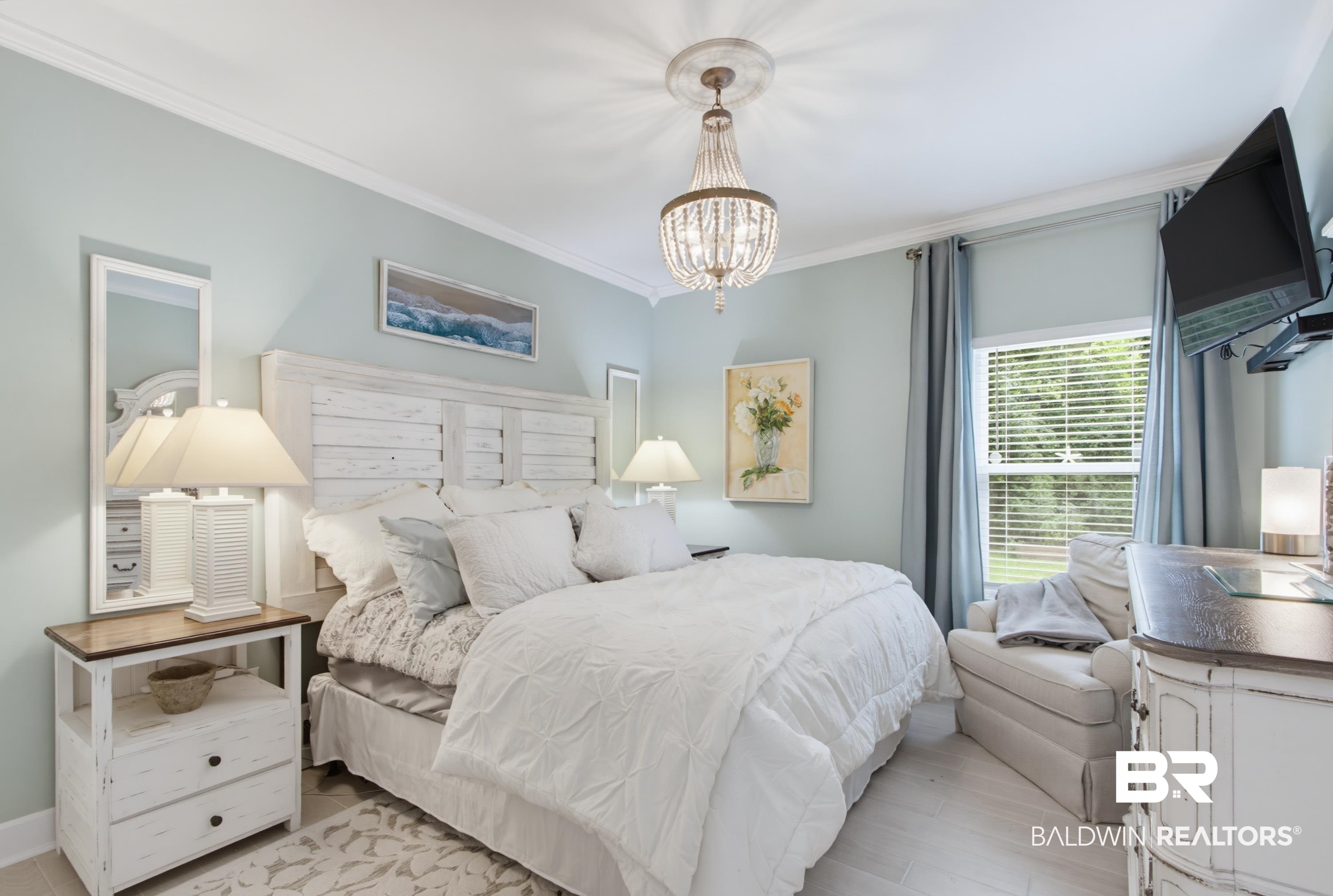 7472 Coopers Landing Road Foley, AL 36535 - Photo 21 of 40 Bedroom featuring a distressed white wood headboard, a crystal chandelier, crown molding, a window with horizontal blinds, and light-colored flooring