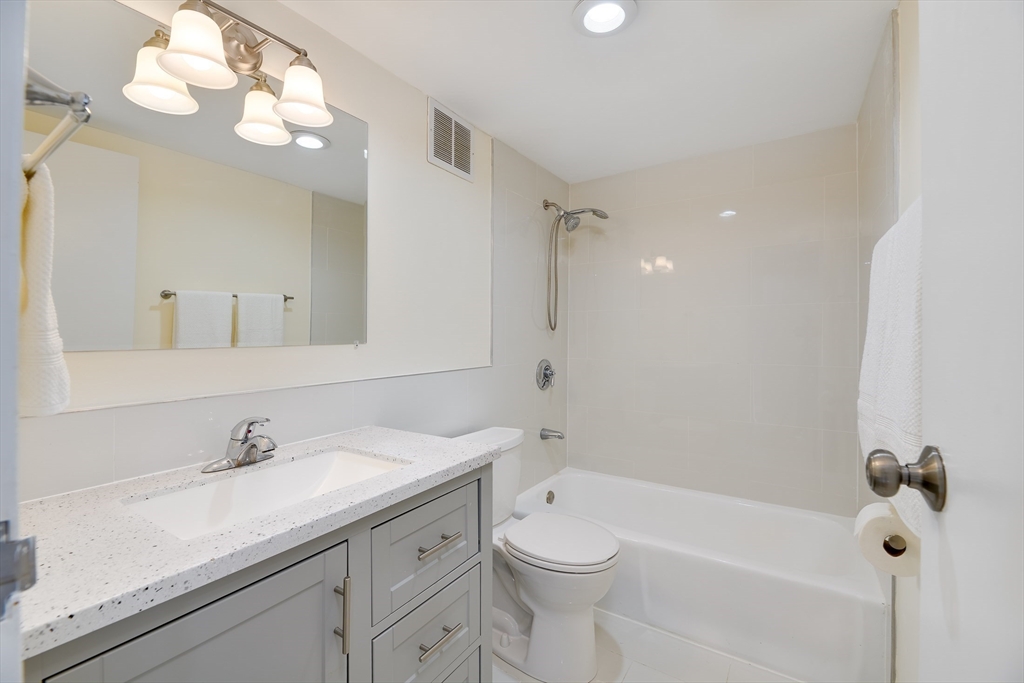 321 Harvard Street, Unit 307 Cambridge, MA 02139 - Photo 14 of 26 a bathroom with a granite countertop sink a toilet and shower