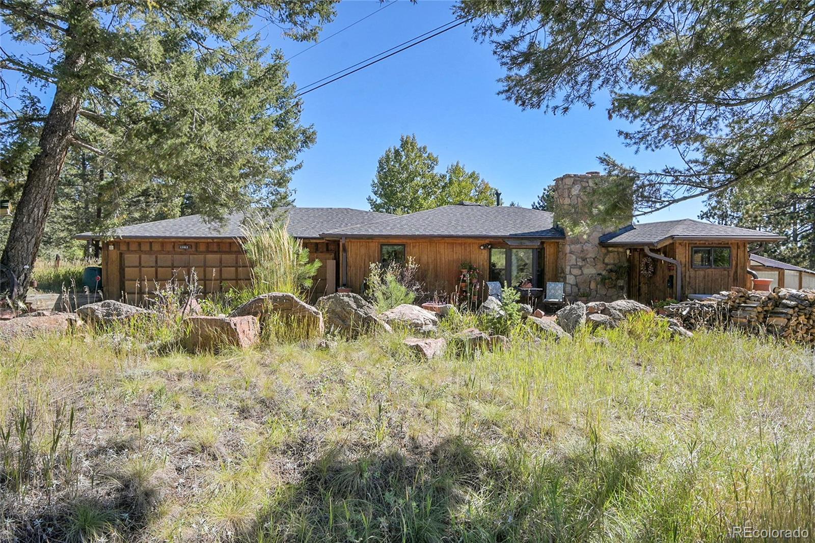 13082 South Wamblee Valley Road Conifer, CO 80433 - Photo 13 of 46 a front view of a house with a yard table and chairs