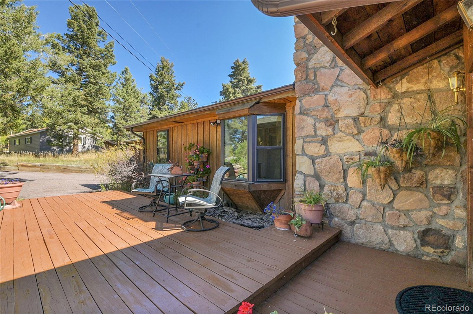 13082 South Wamblee Valley Road Conifer, CO 80433 - Photo 14 of 46 a view of a patio with table and chairs with wooden floor and fence