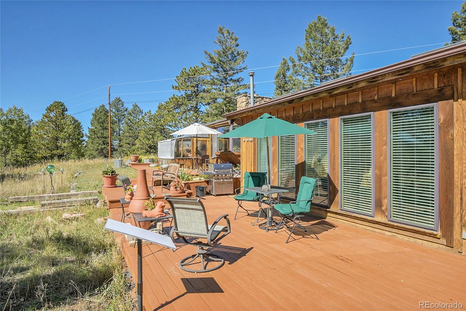13082 South Wamblee Valley Road Conifer, CO 80433 - Photo 5 of 46 a view of a patio with table and chairs and potted plants with wooden floor and fence