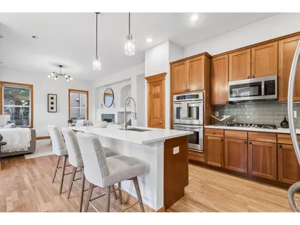 a kitchen with stainless steel appliances granite countertop a sink a stove a dining table and chairs