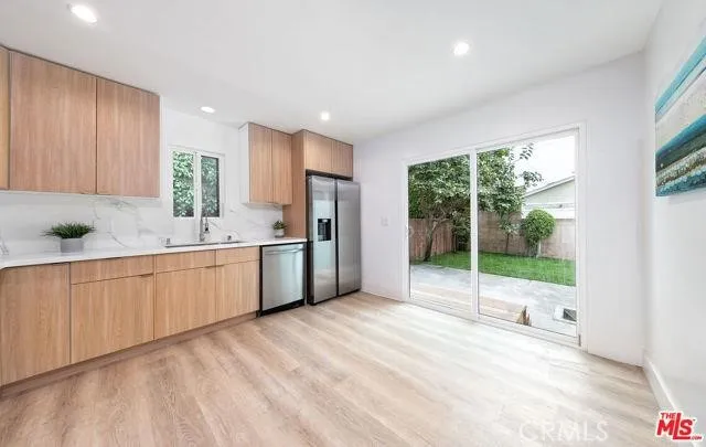a large white kitchen with a sink stainless steel appliances and cabinets