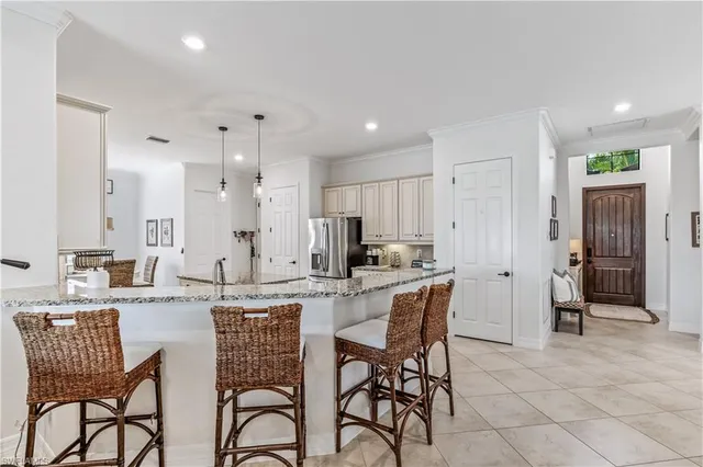 a kitchen with stainless steel appliances kitchen island granite countertop a dining table chairs and a refrigerator