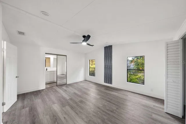 a view of an empty room with window and wooden floor