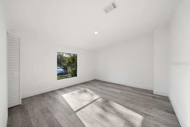 an empty room with wooden floor and windows