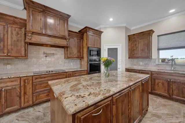 a kitchen with granite countertop kitchen island stainless steel appliances a sink stove and cabinets